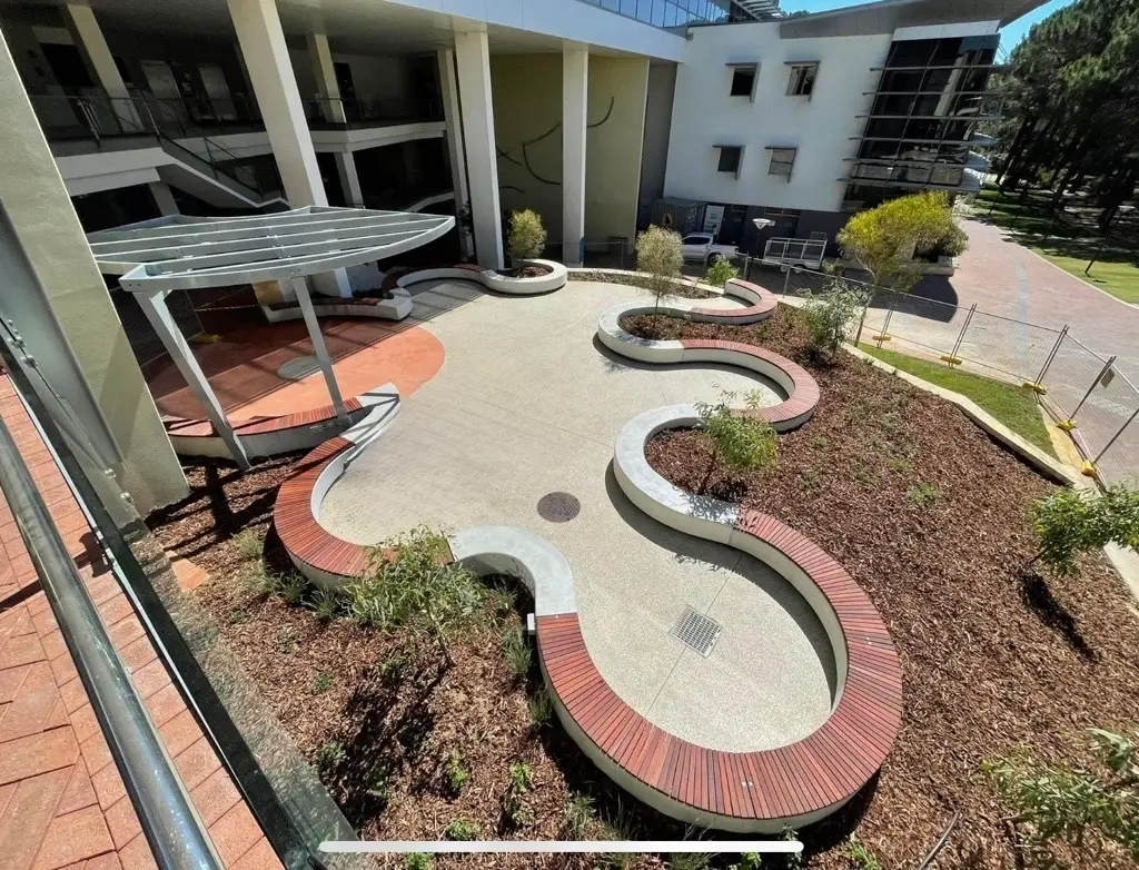 Curved cast-in-situ seating walls with hardwood tops and a shadow gap at ECU