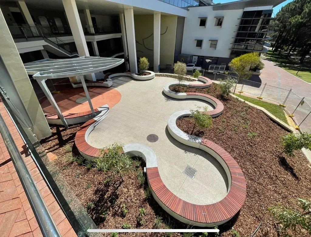 Finished curved concrete seating walls with hardwood timber tops and a shadow gap, in the Edith Cowan University Joondalup courtyard