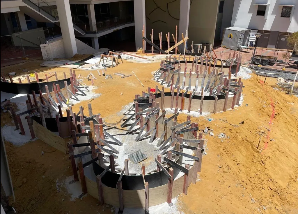 Curved plywood formwork with timber kickers, set out for the seating walls before the pour at Edith Cowan University in Joondalup