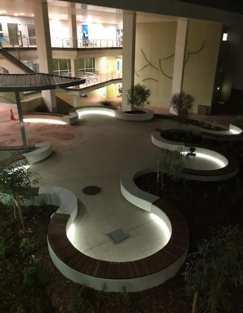 Curved concrete seating walls lit from beneath after dark at ECU