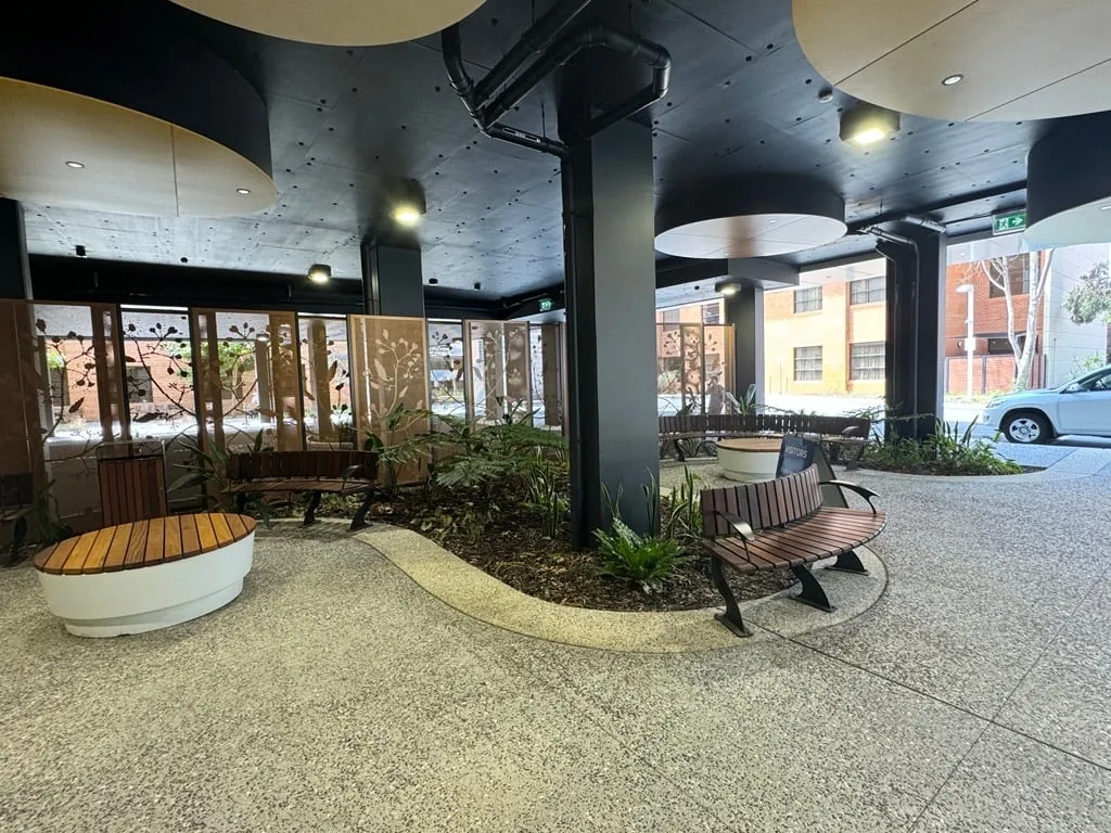 Exposed aggregate forecourt at Hollywood Private Hospital in Nedlands, a pale edge band curving around the planted bed