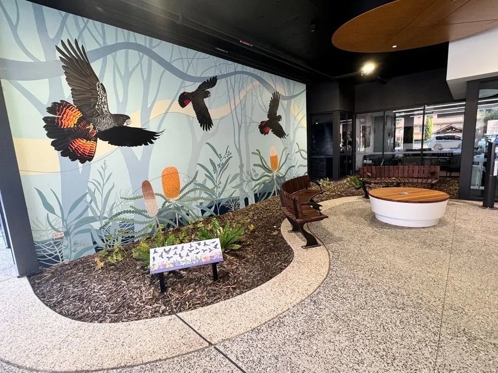 The same exposed aggregate paving sweeping past the black cockatoo mural, edge band following the bed line