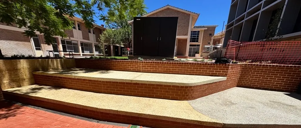 Exposed aggregate terrace steps at PLC, treads running between brick risers to a curved edge