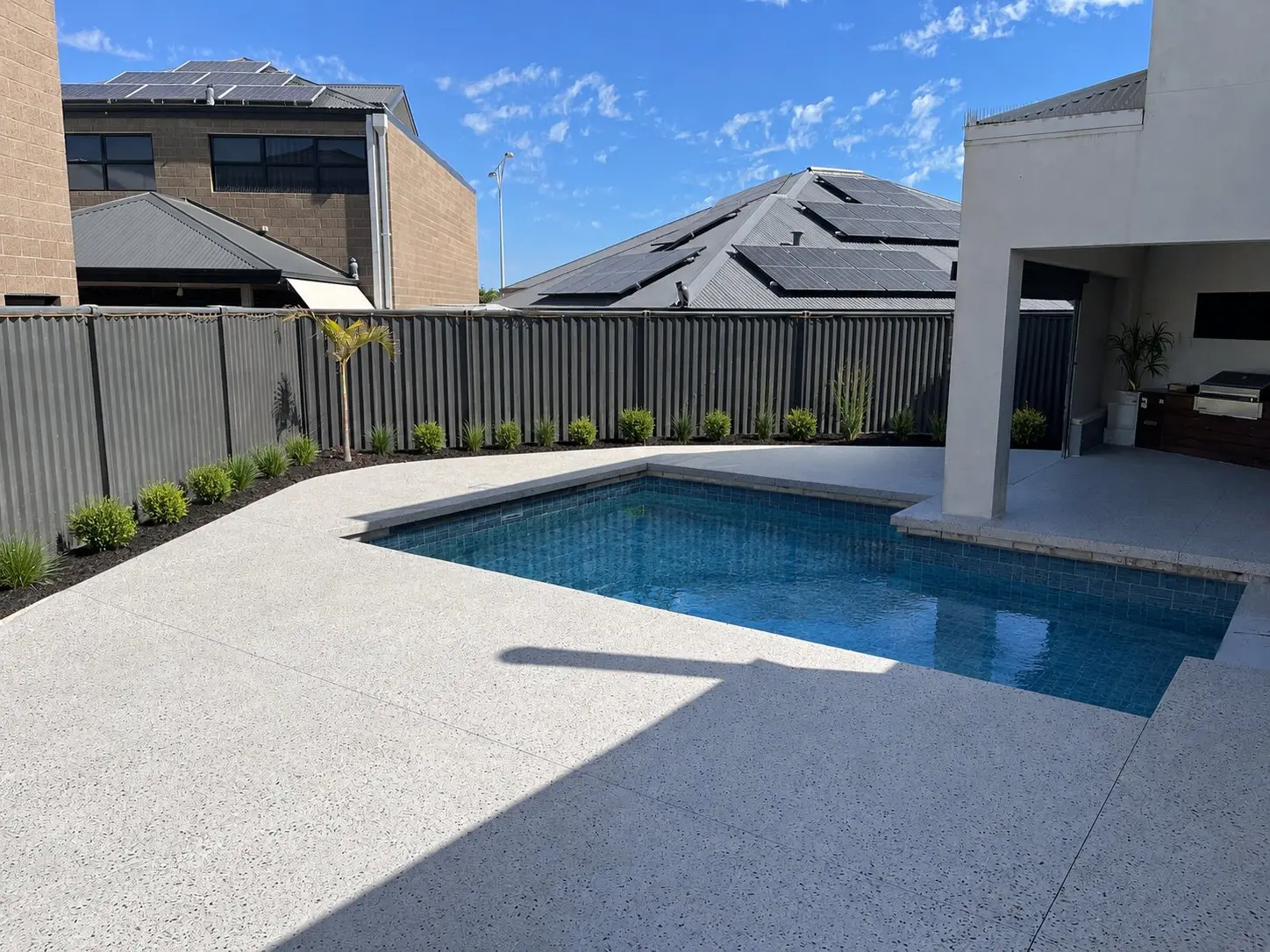 White exposed aggregate pool surround and outdoor kitchen